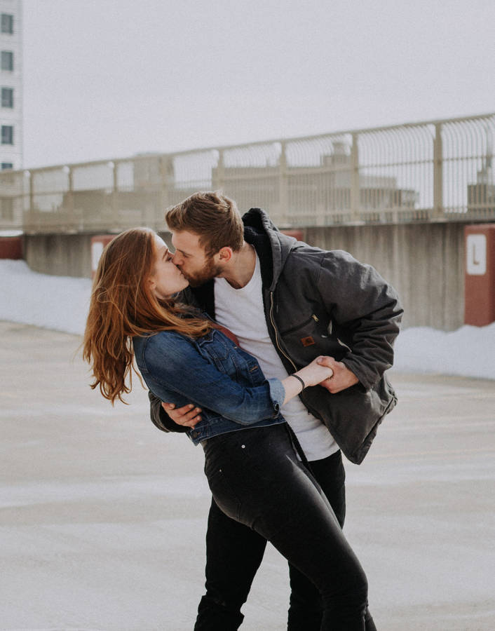 Couple Hugging And Kissing In The Snow Wallpaper