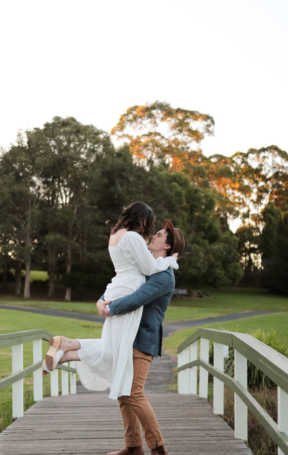 Couple Hugging Catcher Hug On Wooden Bridge Wallpaper