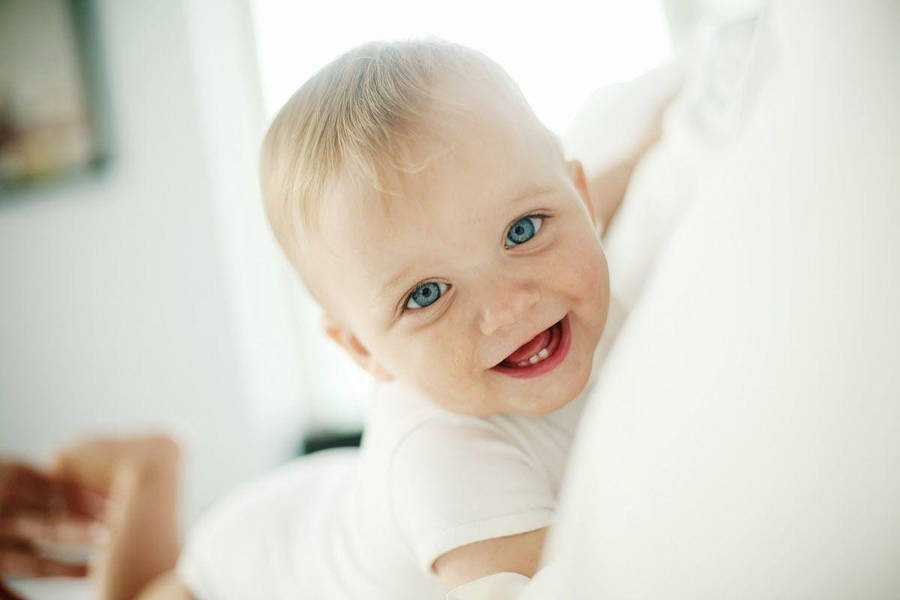 Cute Boy Playing On White Bed Wallpaper