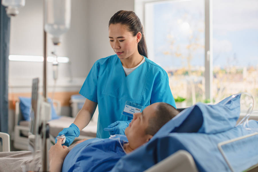 Dedicated Female Nurse Assisting Male Patient Wallpaper