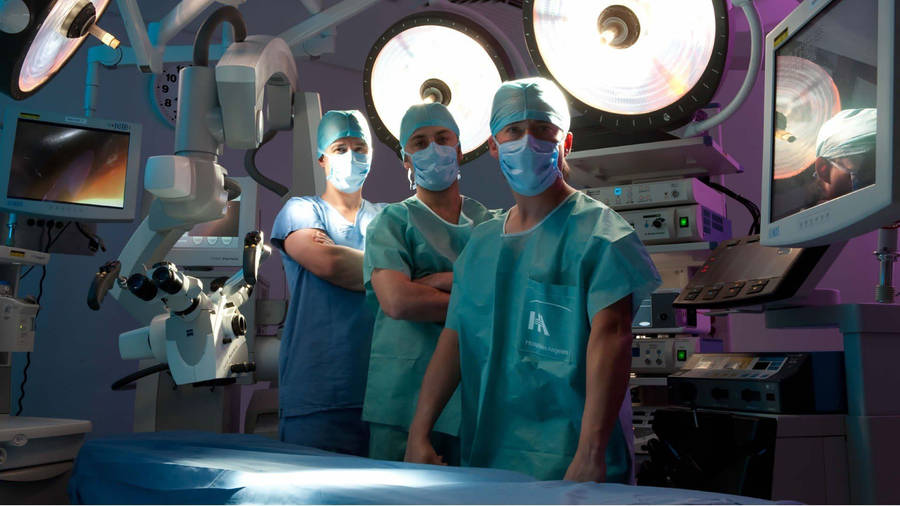 Dedicated Surgeons Performing A Surgery In A High-tech Hospital Operating Room Wallpaper