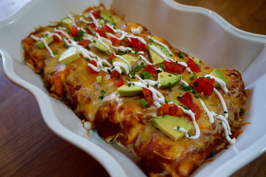 Delicious Enchiladas Topped With Fresh Avocado And Tomato Wallpaper