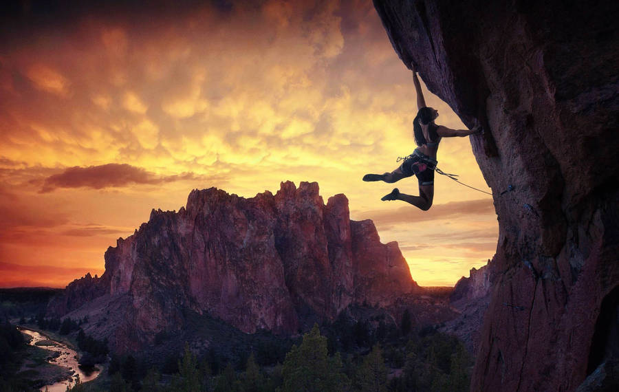 Determined Climber Scaling A Mountain Peak Wallpaper