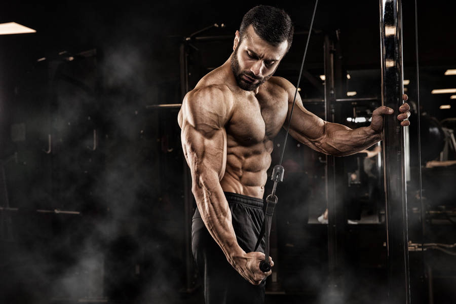 Determined Muscle Man Performing Single Arm Tricep Pushdown Wallpaper