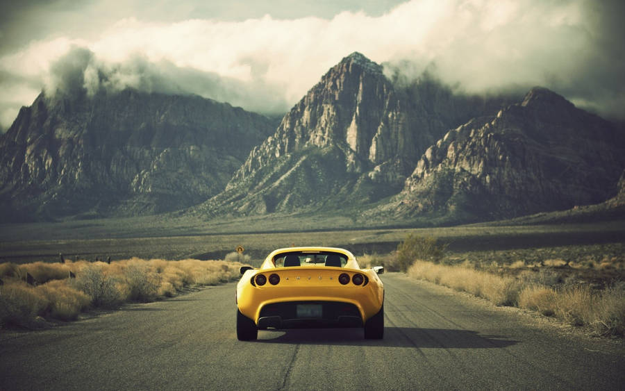 Effortless Power - Yellow Lotus Car Cruising Through The Arid Desert Wallpaper