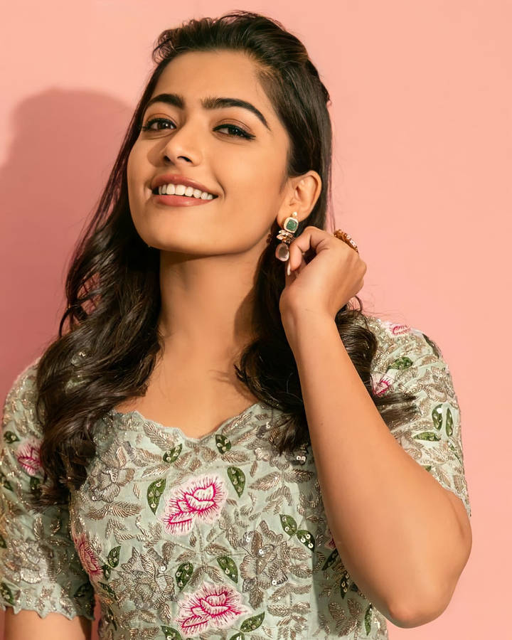 Elegant Rashmika Mandanna In High Definition Against A Pink Backdrop Wallpaper