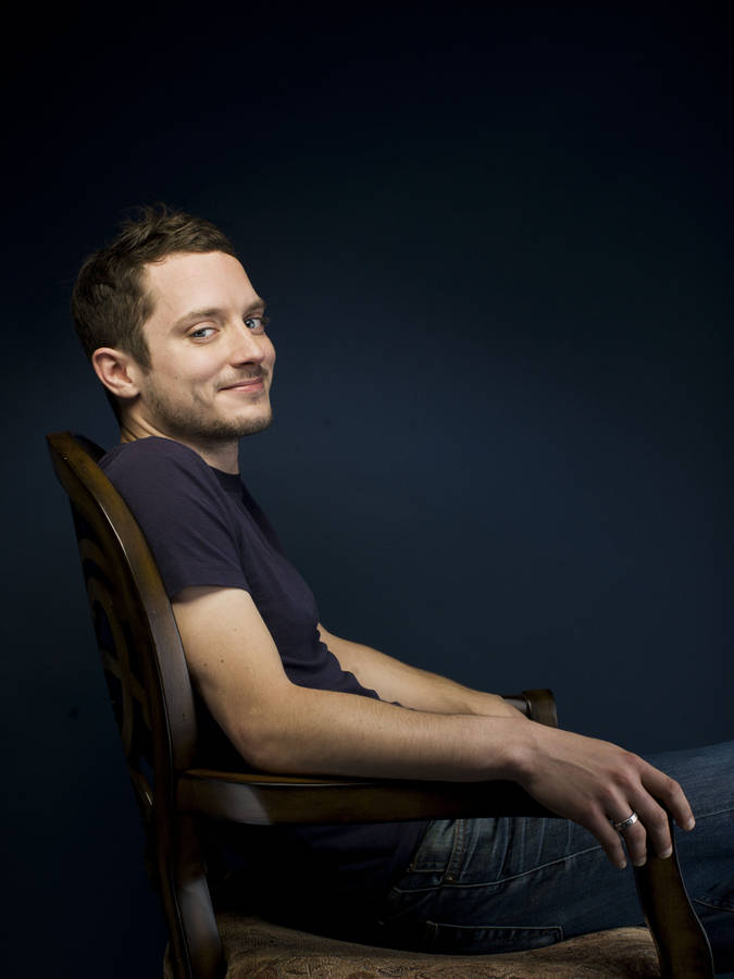 Elijah Wood Seated On A Chair Wallpaper