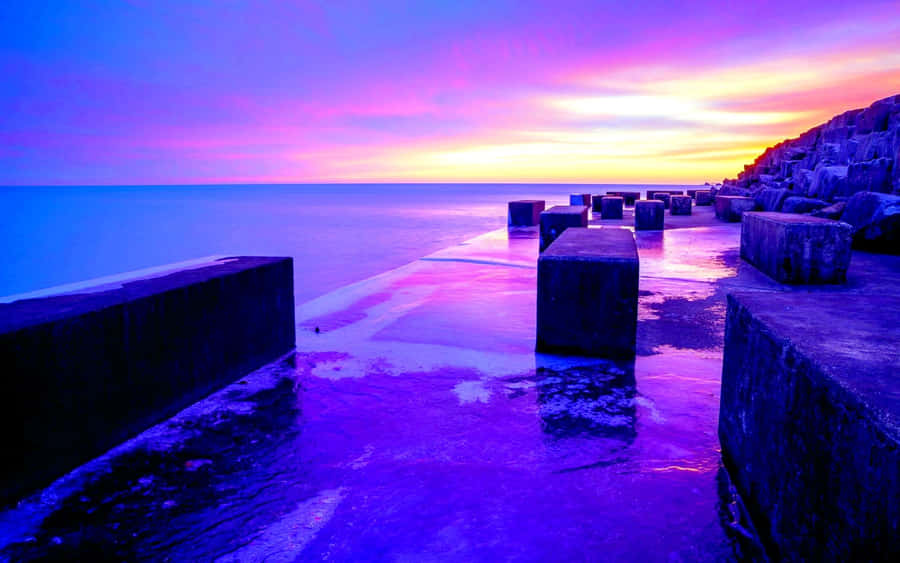 Enjoy The Beauty Of Nature As The Sun Dips Over The Horizon Casting A Beautiful Blue And Purple Sunset. Wallpaper
