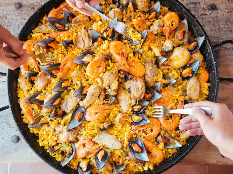 Enjoying Authentic Paella In Pan Wallpaper