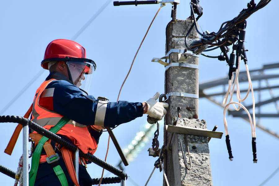 Experienced Electrician Repairing A Power Line Wallpaper