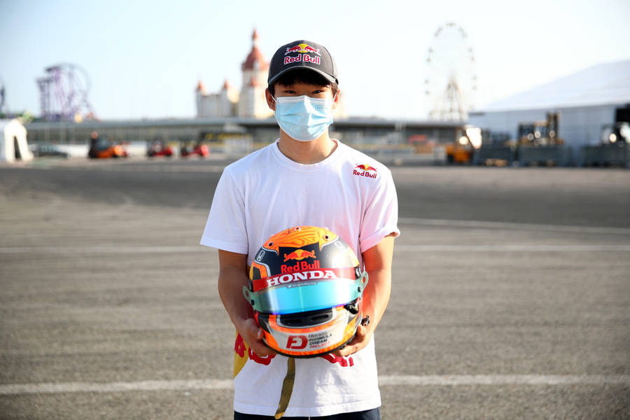 F1 Racer Yuki Tsunoda In Mask Holding Helmet Wallpaper