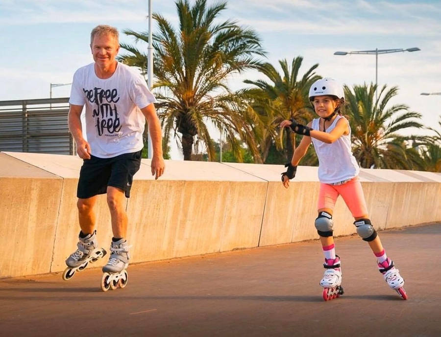 Father And Daughter Enjoying Rollerblading In Park Wallpaper