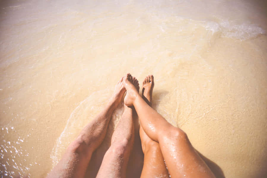 Female And Male Feet On The Seawater Wallpaper