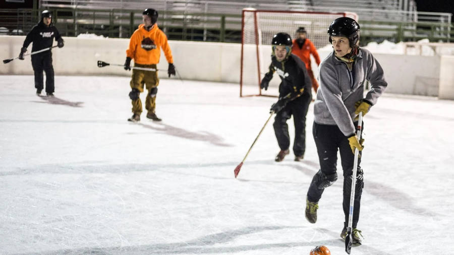 Fierce Woman Athlete In Competitive Broomball Game Wallpaper