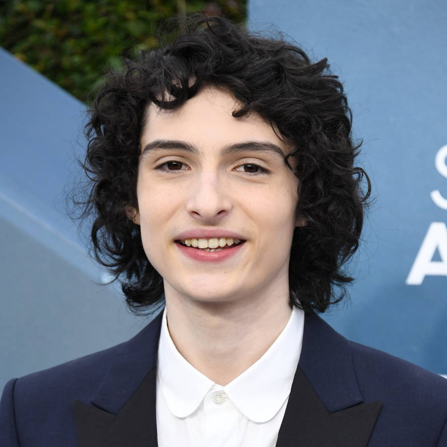 Finn Wolfhard In Coat And Tie Wallpaper