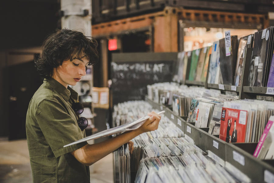 Finn Wolfhard Looking At Records Wallpaper