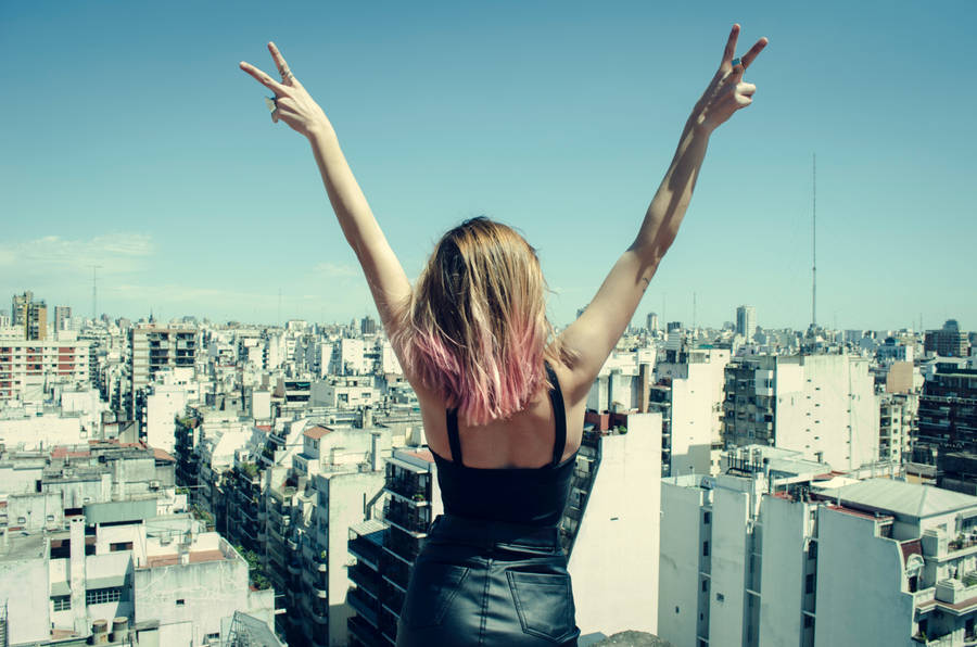 Girl Doing Hand Peace Symbol In City Wallpaper