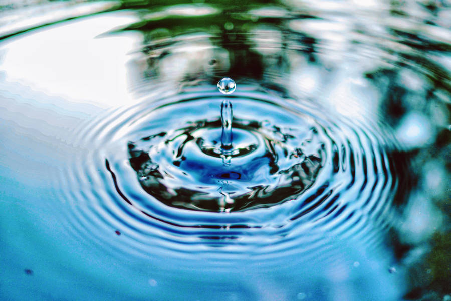 Glistening Droplet Creating Ripples Wallpaper