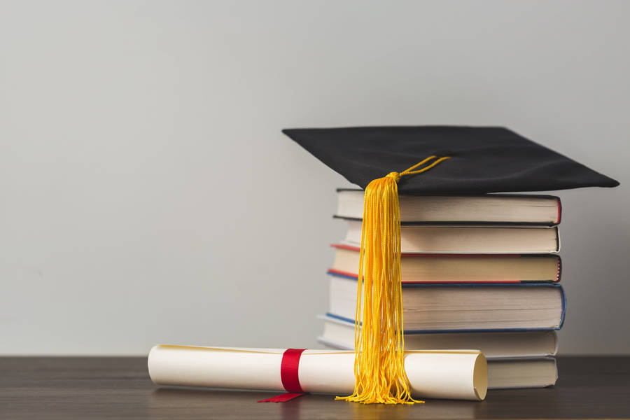 Graduate Cap On Top Of Reference Books Near A Diploma Wallpaper