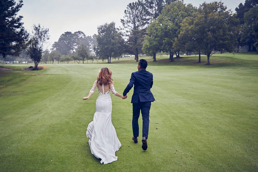 Groom And Bride Running On Golf Course Wallpaper