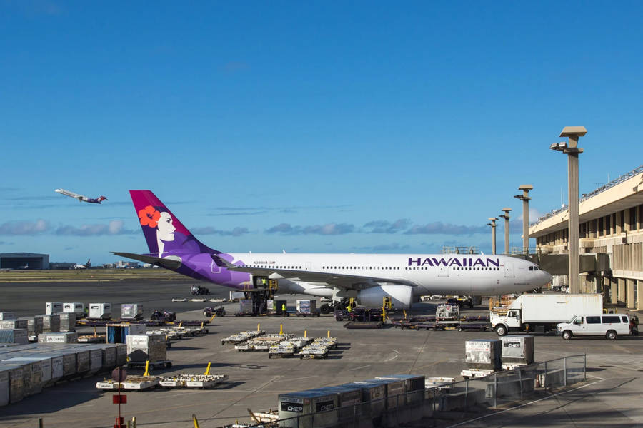 Hawaiian Airlines Plane Amidst A Busy Tarmac Wallpaper