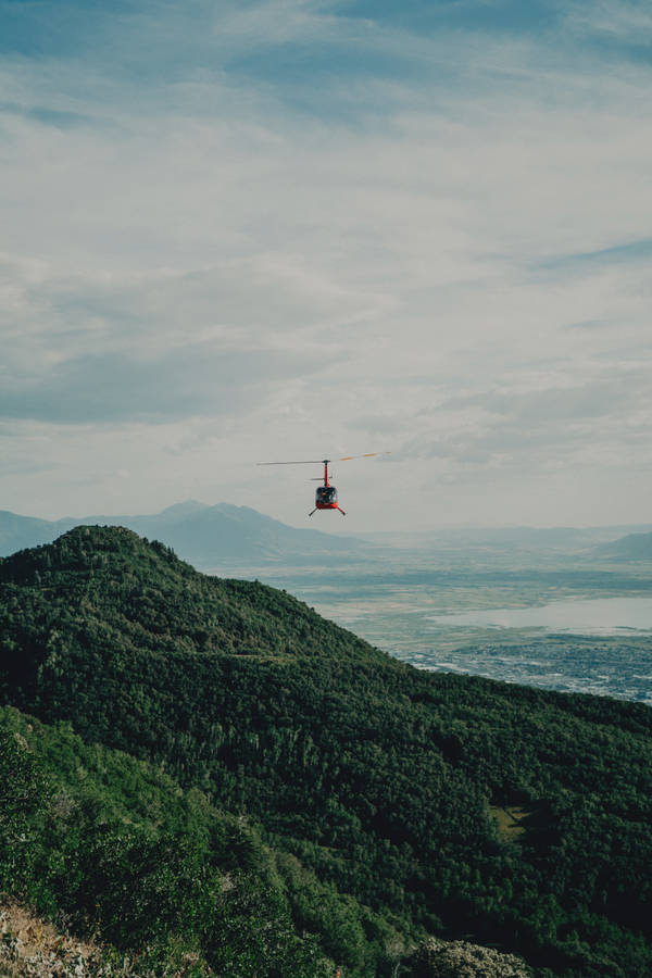 Helicopter Flying Above Green Hills Wallpaper