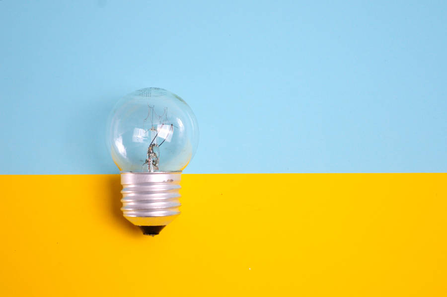 Illuminated Light Bulb Against Bright Background Wallpaper