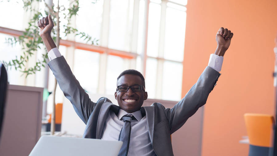 Inspiring Joy - Jubilant African Man With Hands Raised Wallpaper