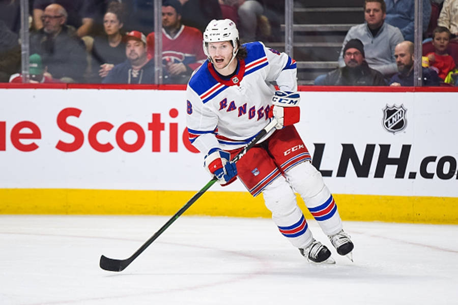 Jacob Trouba From New York Rangers Leaning To The Right While Holding Hockey Stick Wallpaper