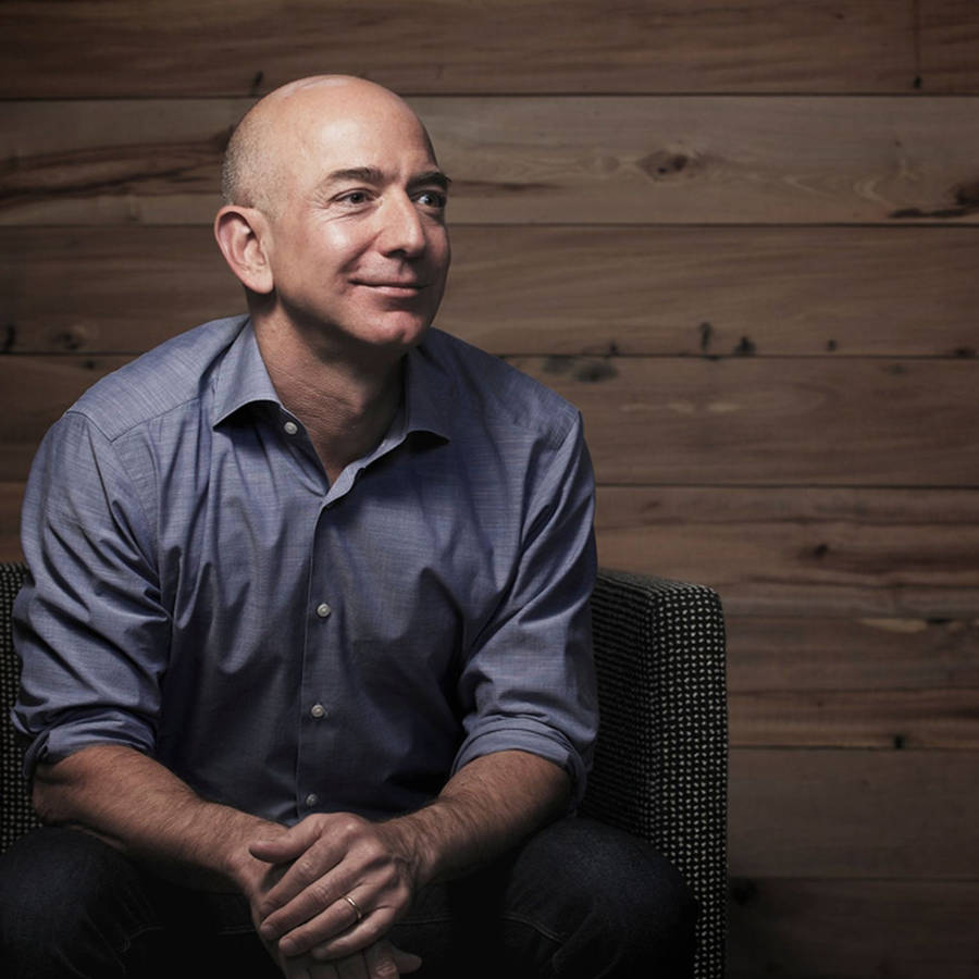 Jeff Bezos Relaxing Against A Wooden Background Wallpaper