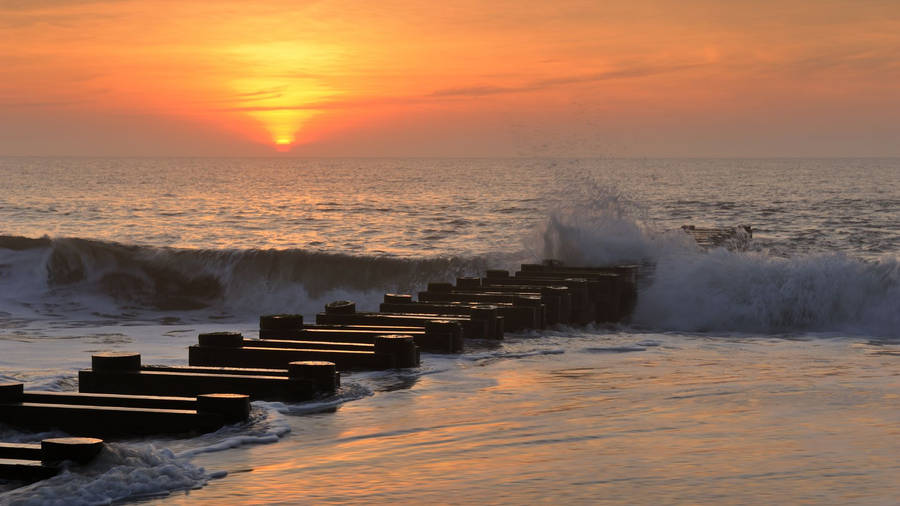 Jetty Pile With Wave On Beach Sunrise Wallpaper