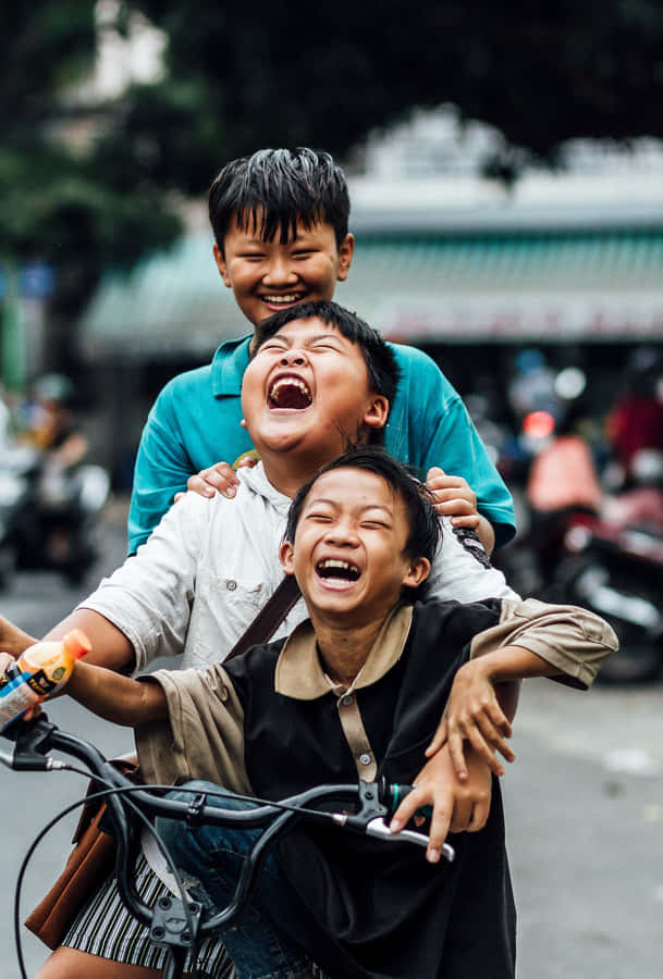 Joyful Children Laughing On Bicycle Wallpaper