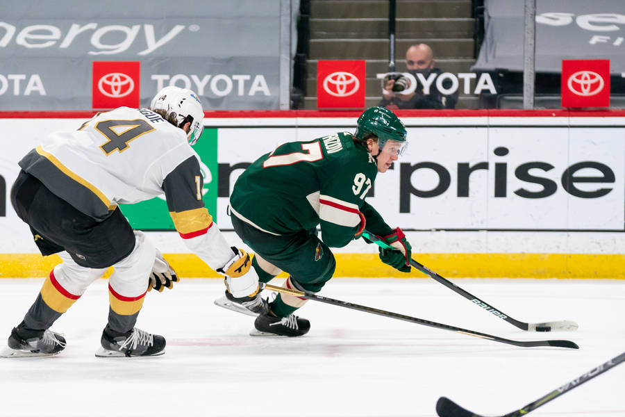 Kirill Kaprizov In Action, Skillfully Fighting For A Puck Amidst A Hockey Game Wallpaper