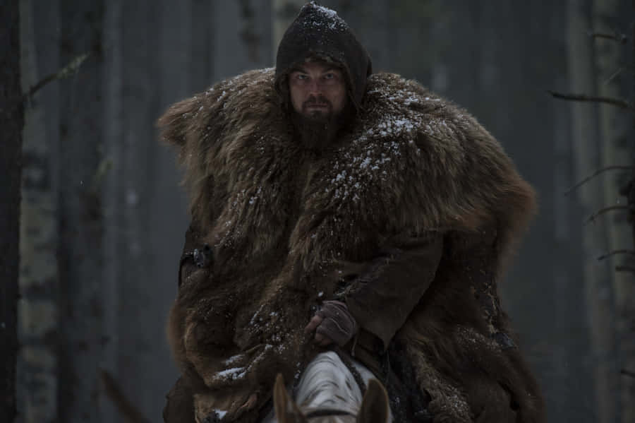 Leonardo Dicaprio In The Revenant Trudging Through Snowy Wilderness Wallpaper