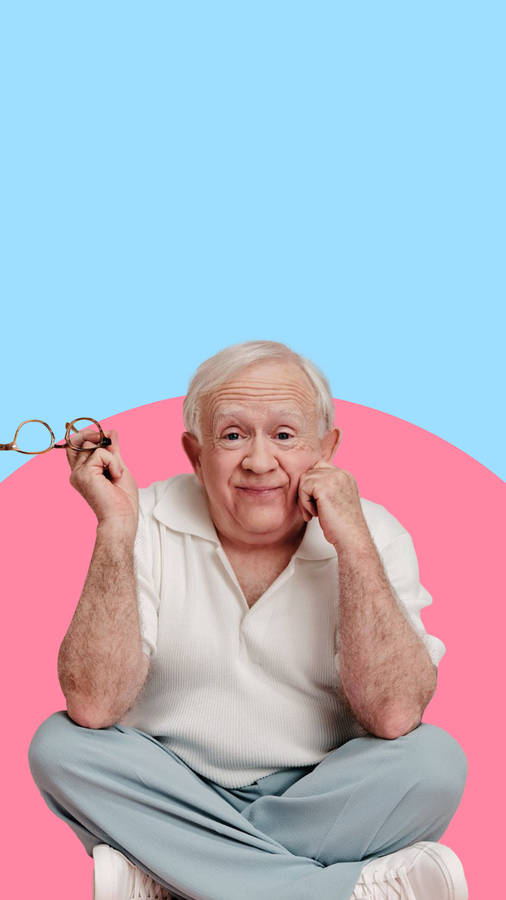 Leslie Jordan Holding Glasses Blue Pink Wallpaper