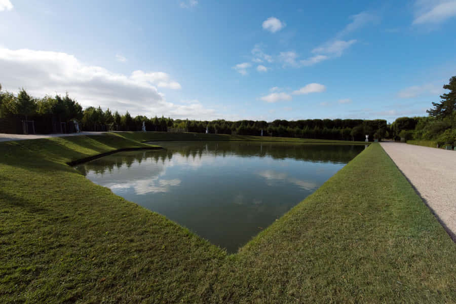 Majestic Mirror Pool Reflecting The Grandeur Of The Palace Of Versailles Wallpaper