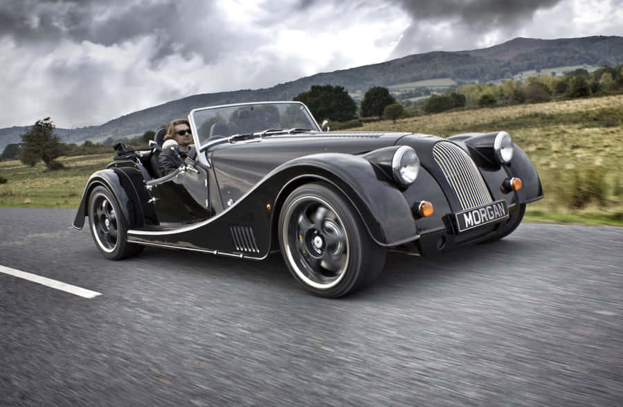 Majestic Morgan Sports Car On A Scenic Road Wallpaper