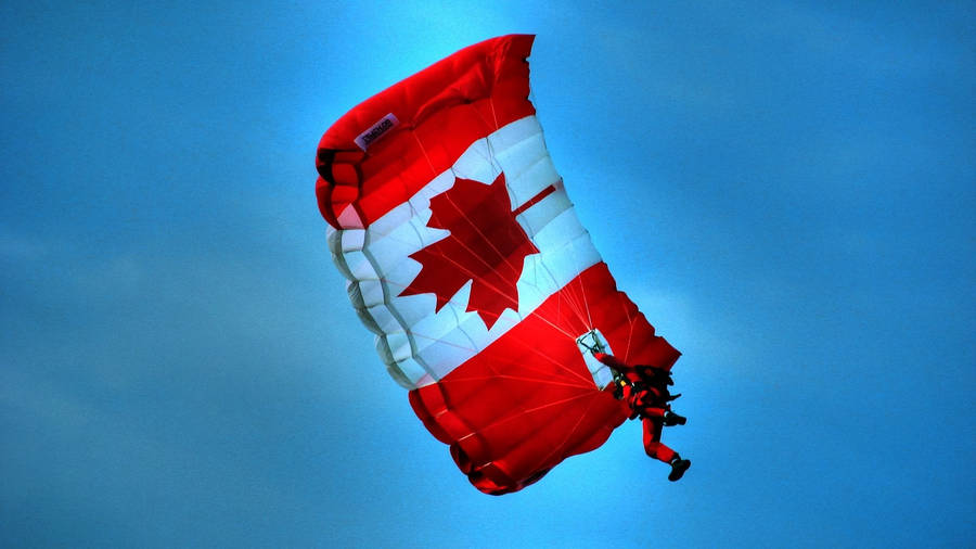 Majestic Shot Of Canada Flag Floating On A Parachute Against The Blue Sky Wallpaper