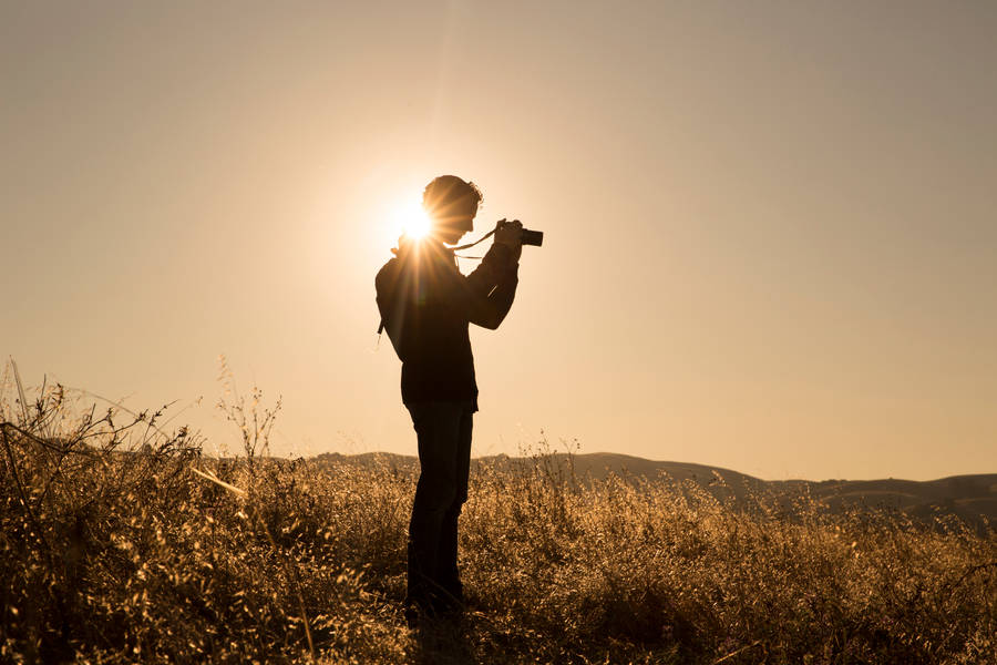 Man Holding Camera During Sunrise Photography Wallpaper