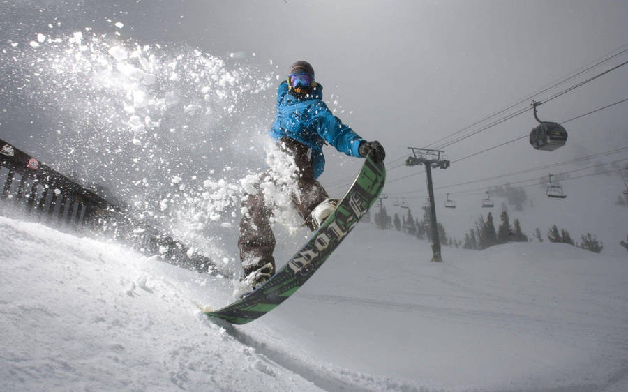 Man In Blue With A Snowboard Leaping Wallpaper