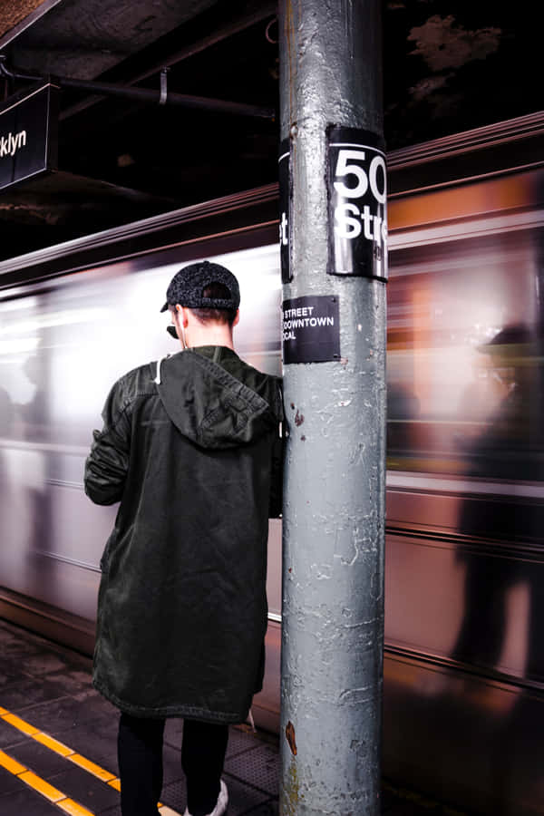 Man Leaning On A Post While Waiting Wallpaper