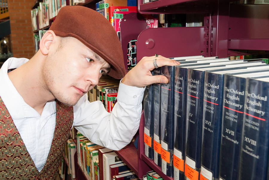 Man Looking At Oxford Dictionary Reference Wallpaper