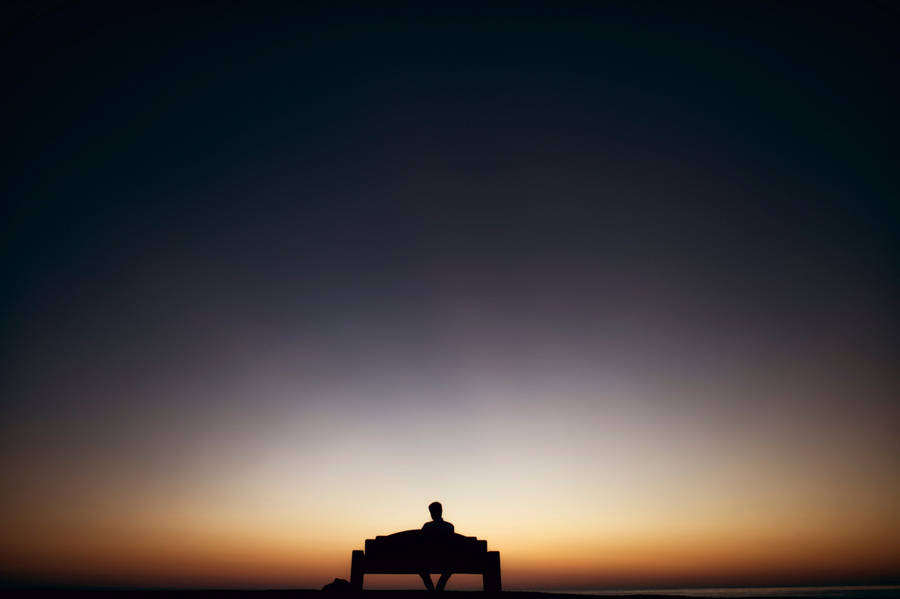 Man Sitting Alone Under Gradient Sky Wallpaper