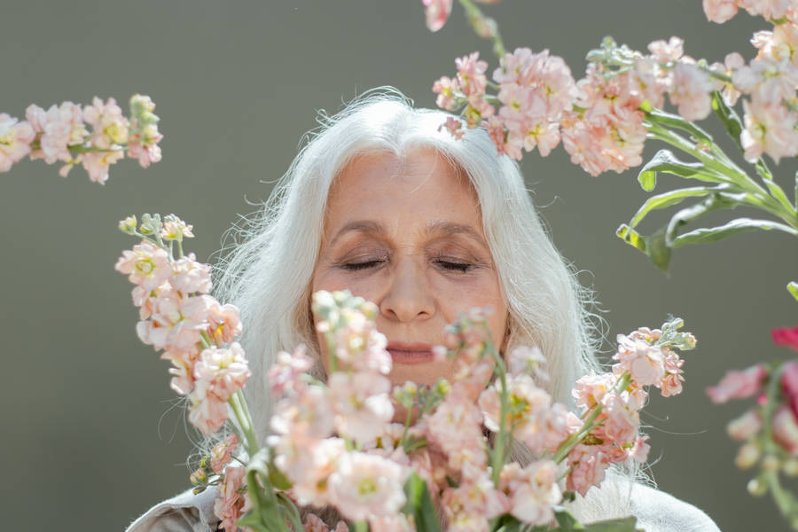 Mature Woman Surrounded By Flowers Wallpaper