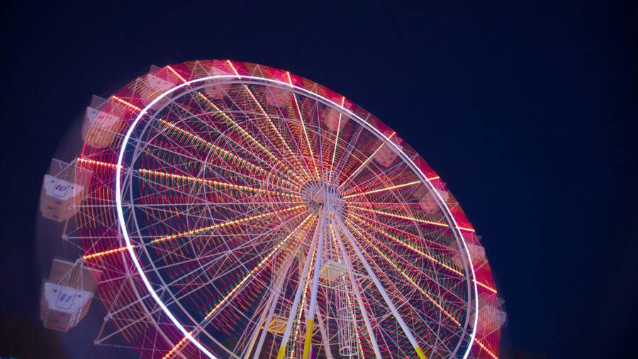 Mesmerizing Display Of Neon Lights On Ferris Wheel Wallpaper