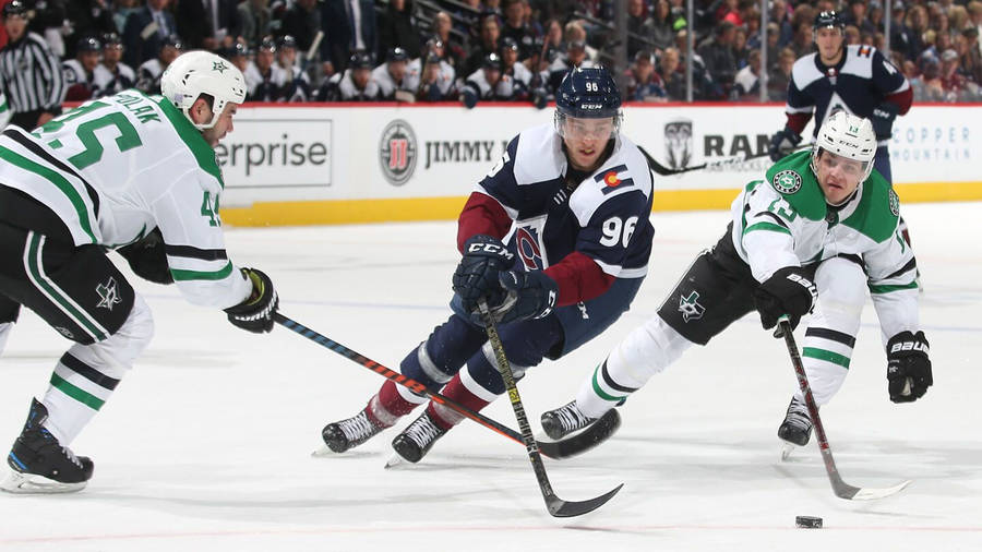 Mikko Rantanen Dribbling Hockey Puck Against Dallas Stars Players Wallpaper