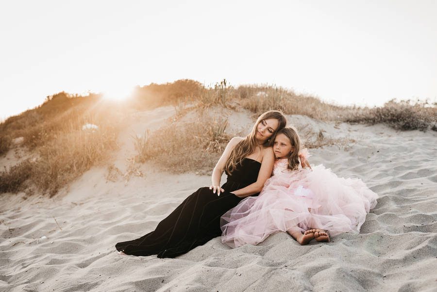 Mother And Daughter Sitting By The Beach Wallpaper