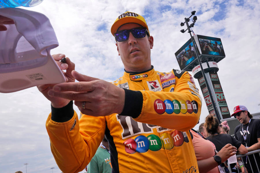 Nascar Champion Kyle Busch Autographing A Fan's Cap Wallpaper