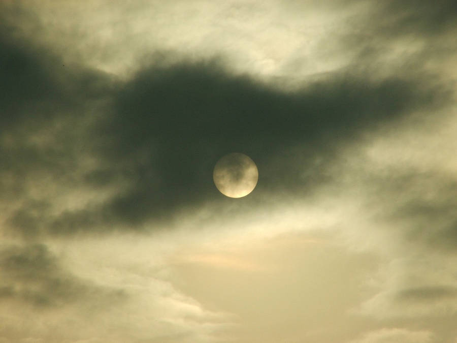 Ominous Moon Behind Dark Clouds Wallpaper