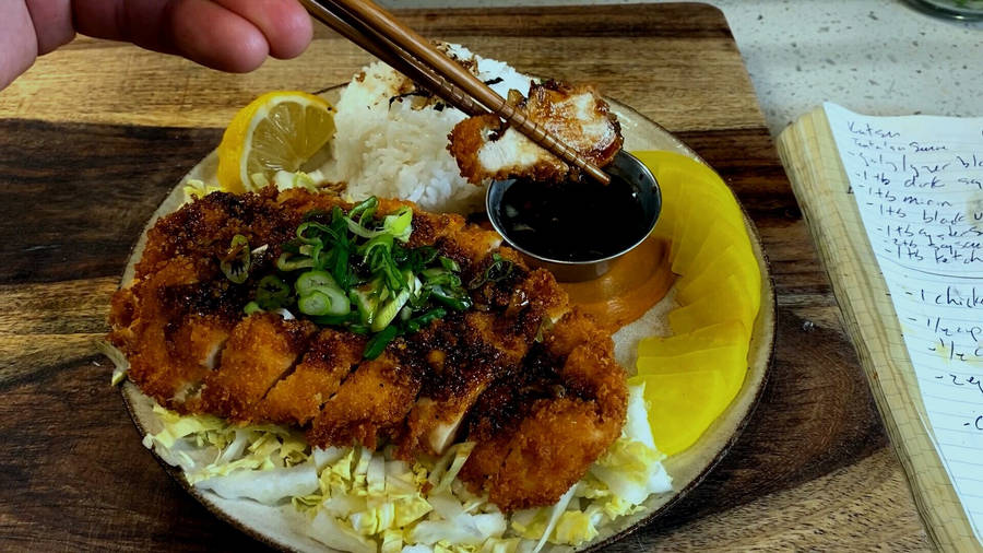 Person's Hand Pinching A Tonkatsu Using Chopsticks Wallpaper